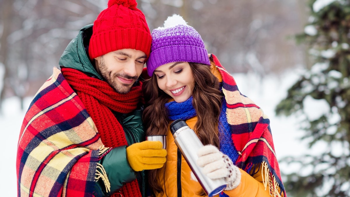 couple drinking out of thermos in cold winter weather