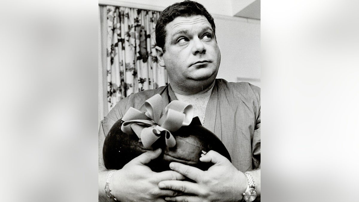 Jackie Vernon memegang semangka yang memiliki busur.