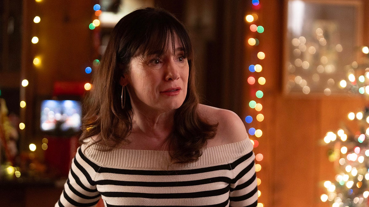 Jill Schoelen in a striped black and white sweater looking surprised during Christmas.