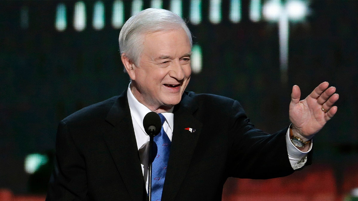 Jim Hunt sorri e acena de terno