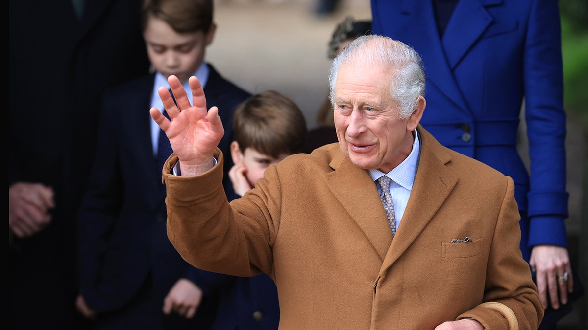 King Charles waving in a tanned wool coat.