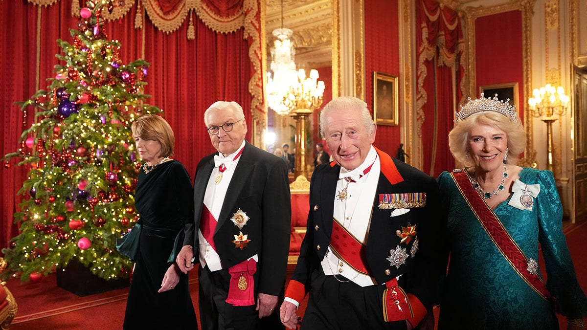King Charles and Queen Camilla in royal regalia inside Buckingham Palace.