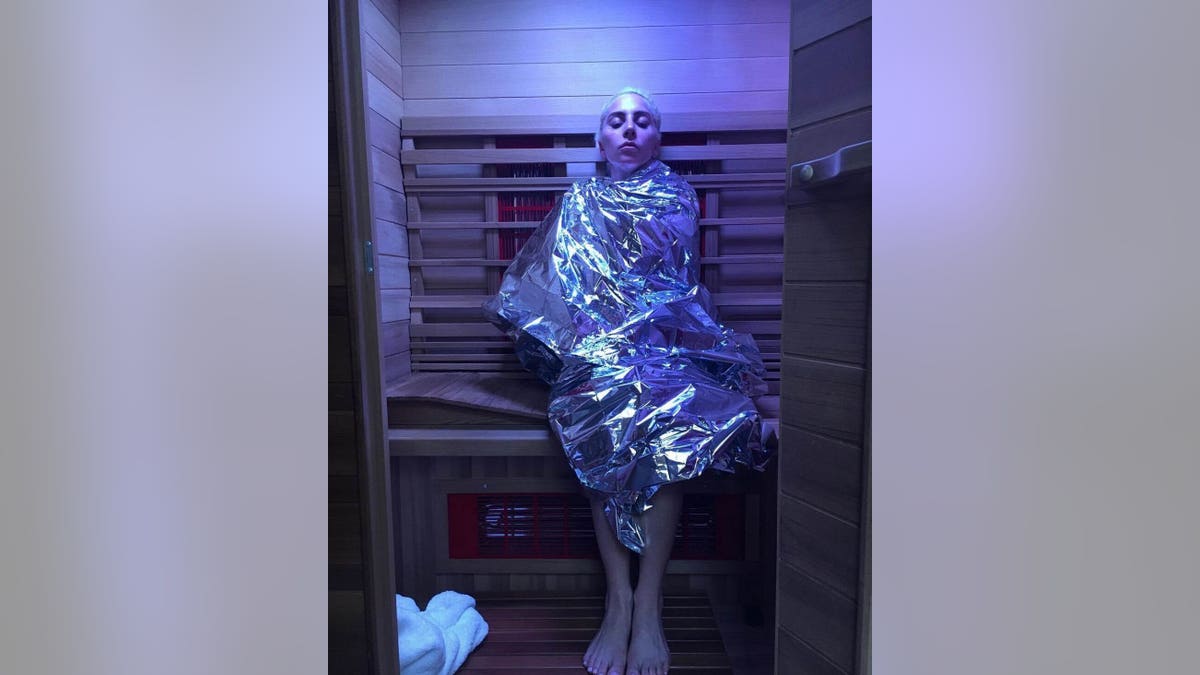 Lady Gaga wrapped in a metallic blanket in a sauna.