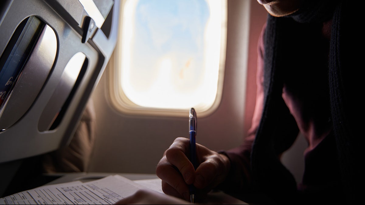 A man fills out immigration form on airplane.