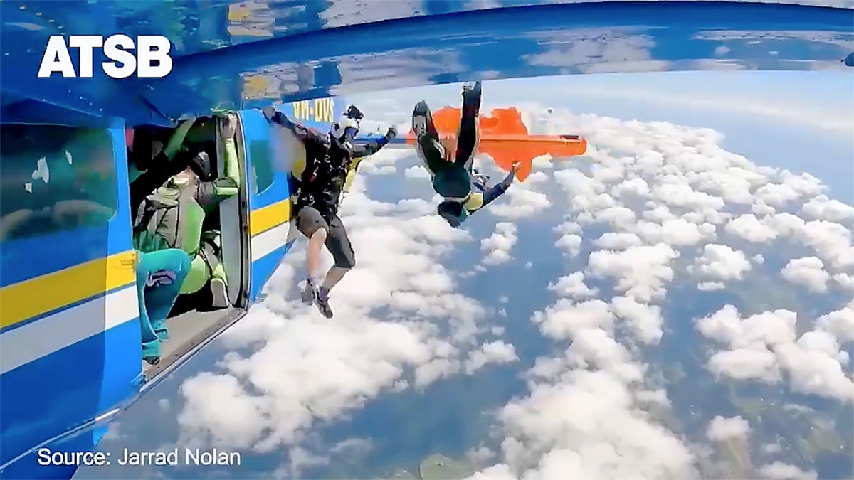 Two skydivers exit a bluish craft arsenic an orangish reserve parachute deploys supra scattered clouds and gets caught connected the airplane's wing.