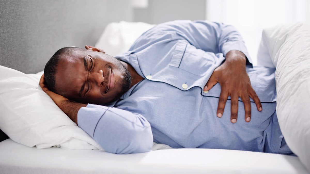 Man lying down in bed with heartburn