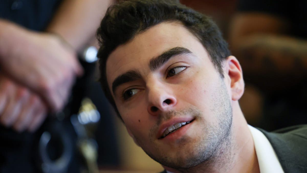 Luigi Mangione leans in court with a 5 o'clock shadow