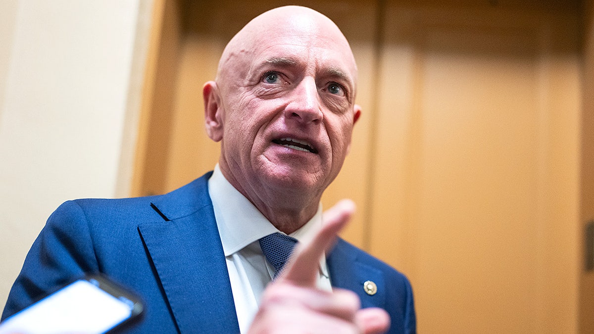 Sen. Mark Kelly speaks with reporters while walking through the Senate subway at the U.S. Capitol.
