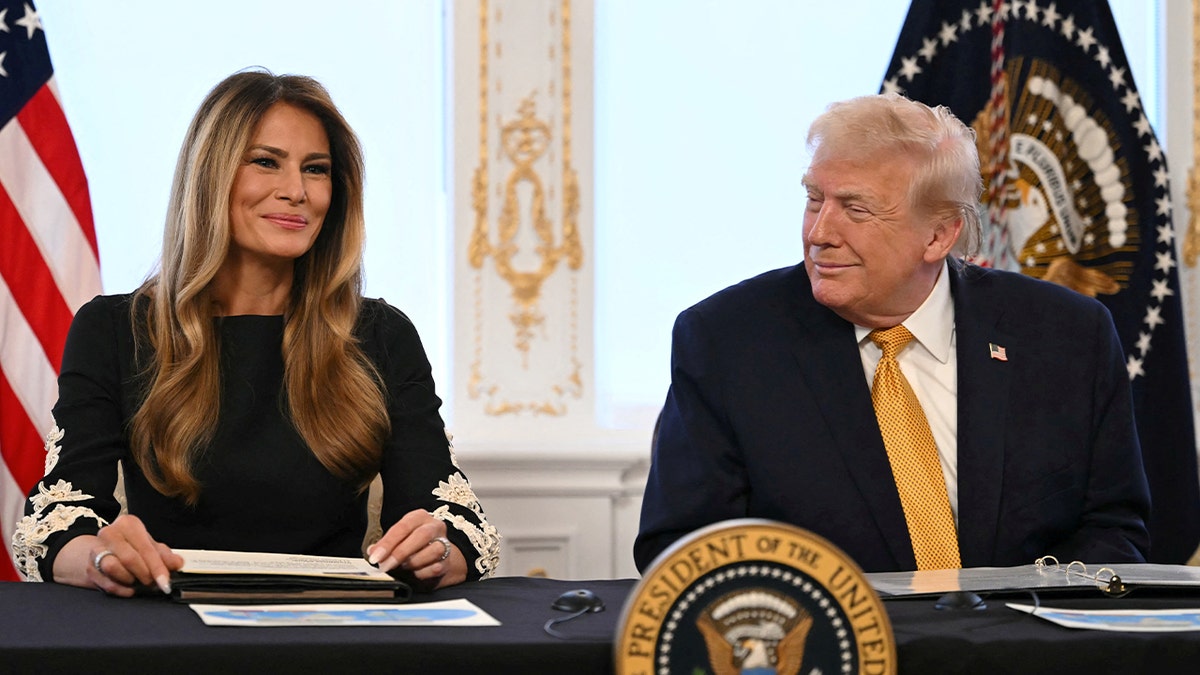 Ibu Negara Melania Trump tersenyum sambil duduk di sebelah Presiden Donald Trump yang tersenyum padanya