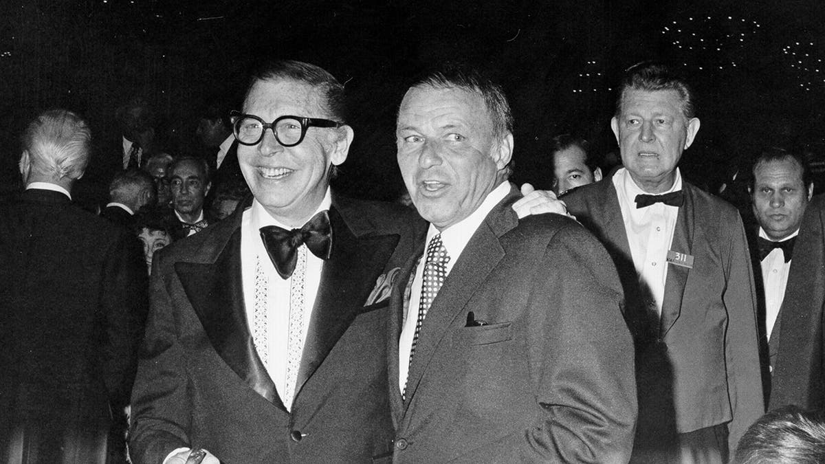 Milton Berle and Frank Sinatra standing together in suits.