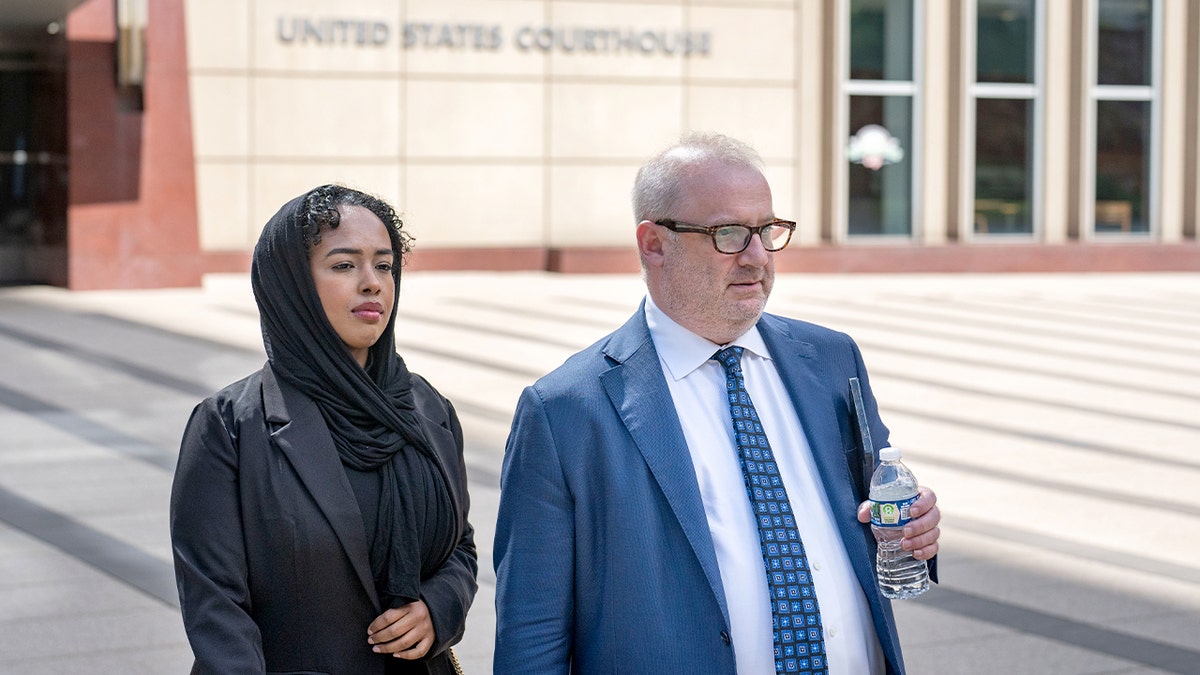 A woman accused of attempting to bribe a juror leaves a federal courthouse with her lawyer after entering a guilty plea.