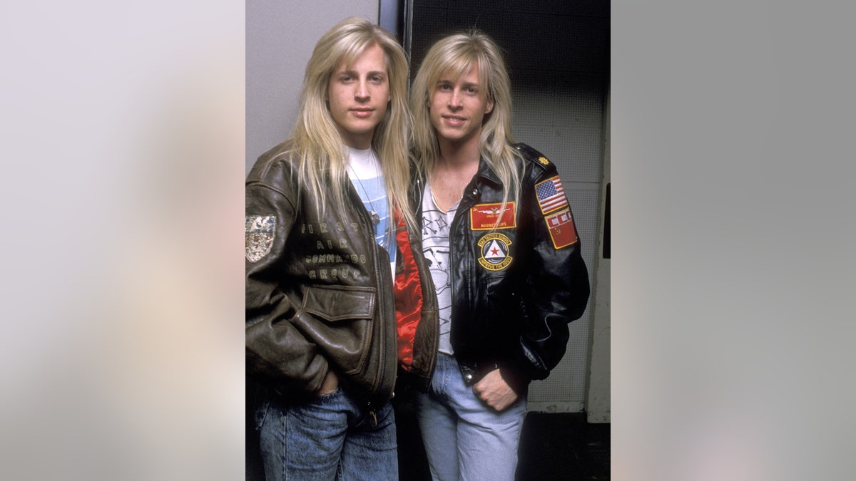 Los gemelos Nelson juntos, con chaquetas de cuero negro y vaqueros azules.