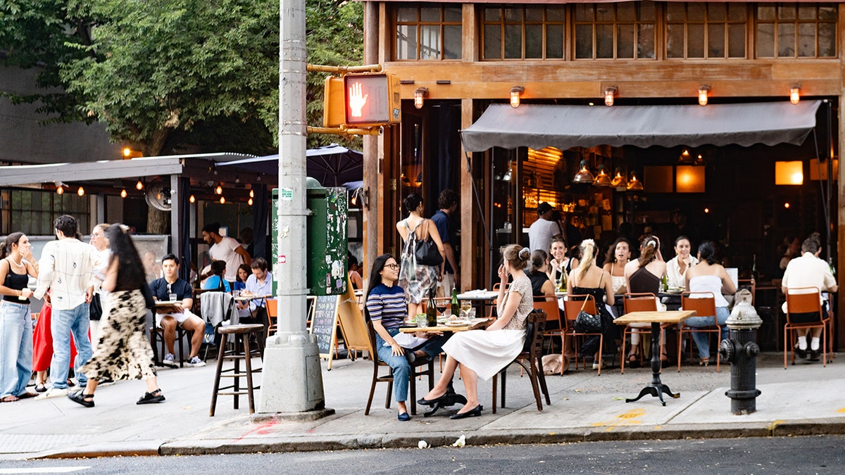 People dining outdoors in NYC on warm day.