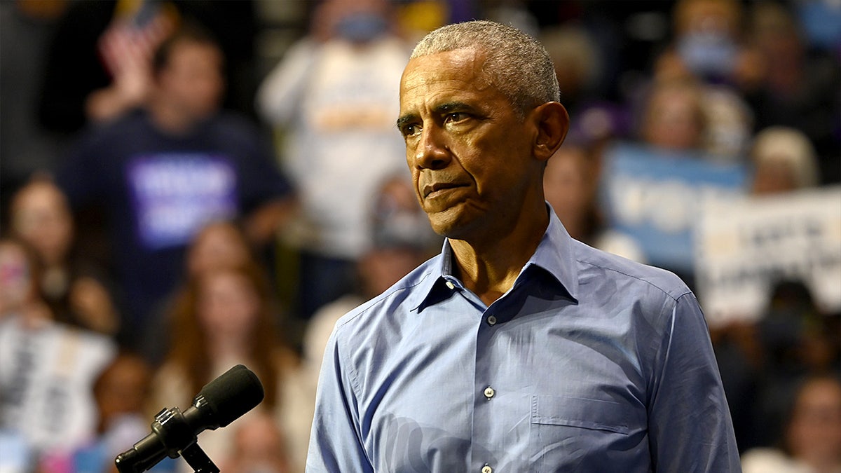 Former President Barack Obama speaks to supporters during a rally inside a college gymnasium.