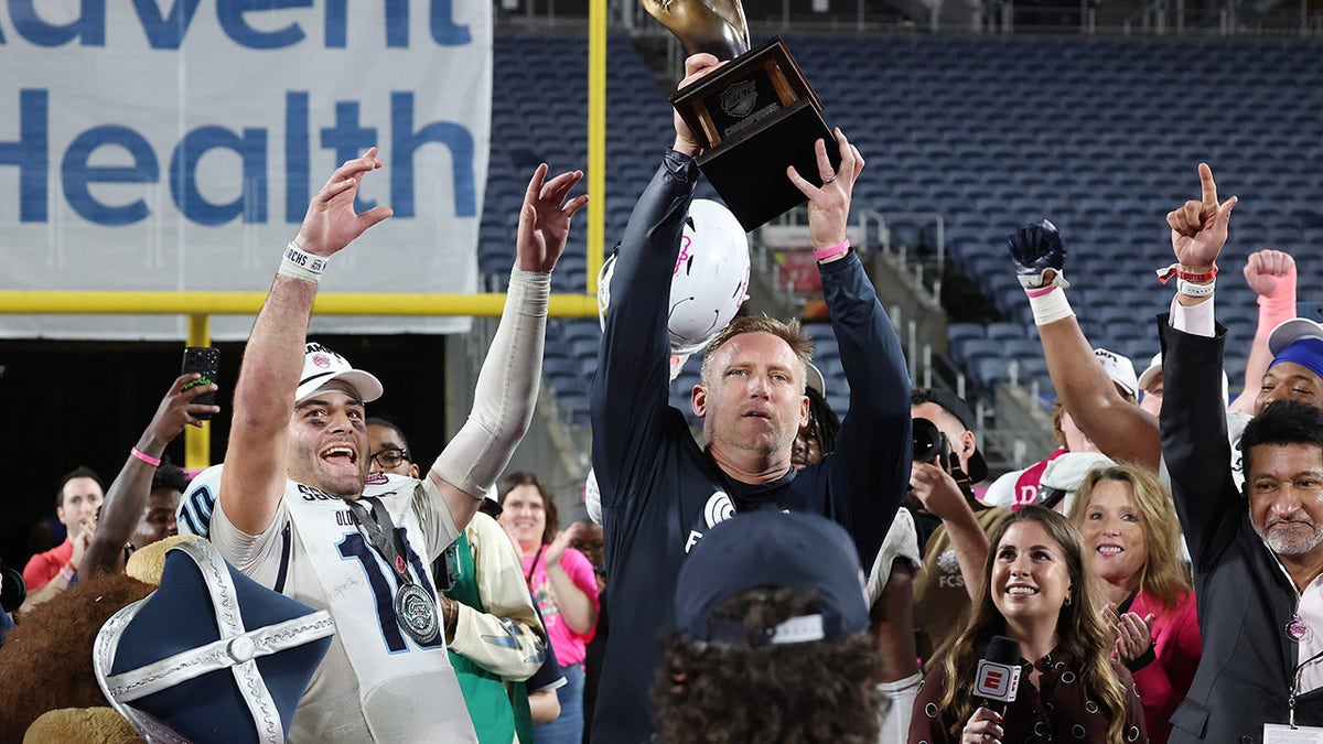 Ricky Rahne holds the Cure Bowl trophy