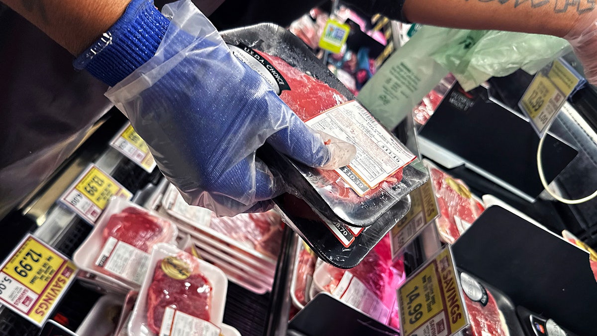 grocery worker holds a packet of steak
