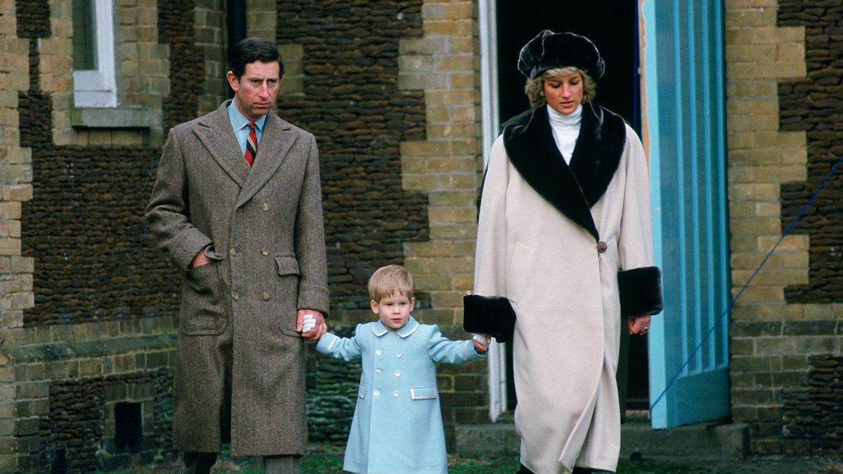 Prince Charles and Princess Diana holding a young Prince Harry at Sandringham.