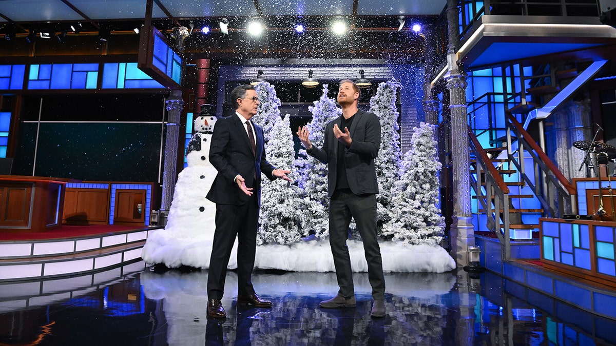Stephen Colbert and Prince Harry admiring fake snow on set.