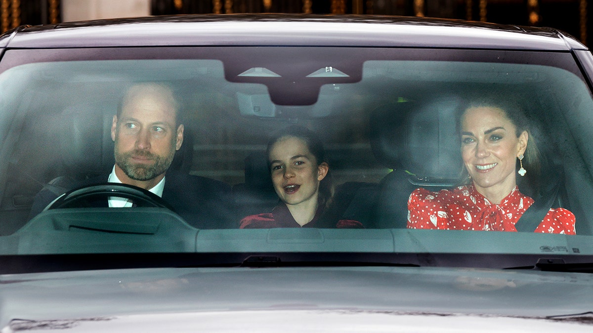 Prince William driving a car with his wife Kate Middleton and their daughter Princess Charlotte inside.