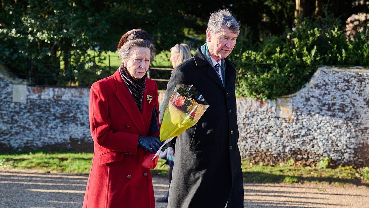 Princess Anne wearing a red coat and holding onto a bouquet of flowers.