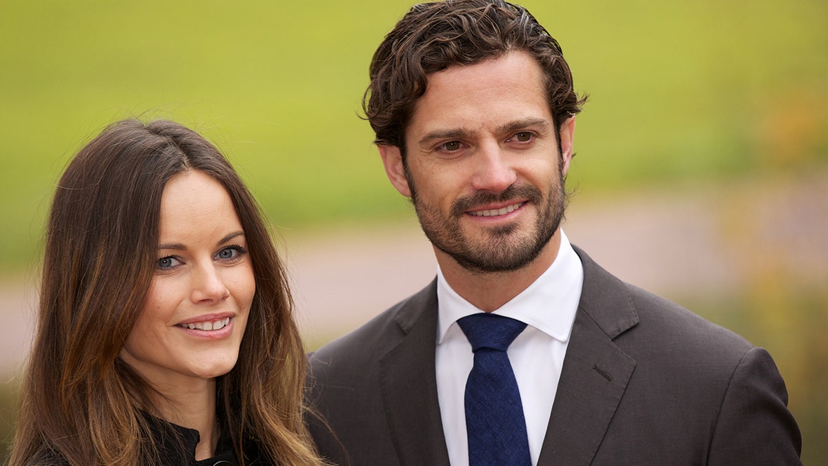 Princess Sofia and Prince Carl Philip next to each other smiling in formal wear outdoors during a royal engagement.