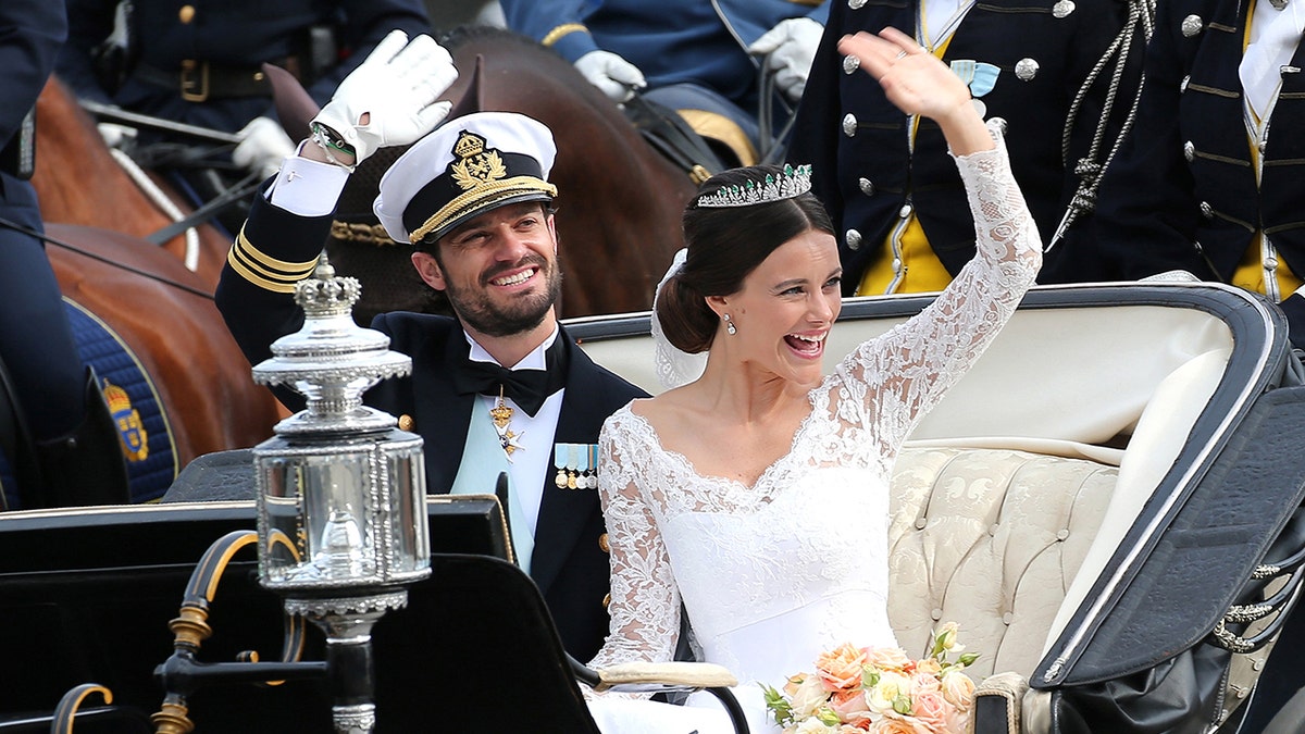 Princess Sofia and her husband Prince Carl Philip waving on their wedding day from a royal carriage.