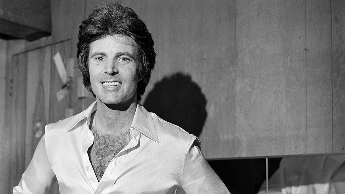 Ricky Nelson smiling wearing a partially opened shirt.