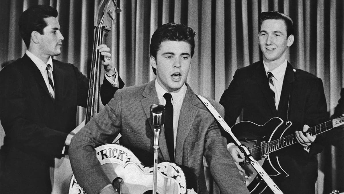 Teen idol Ricky Nelson playing with his band on stage.