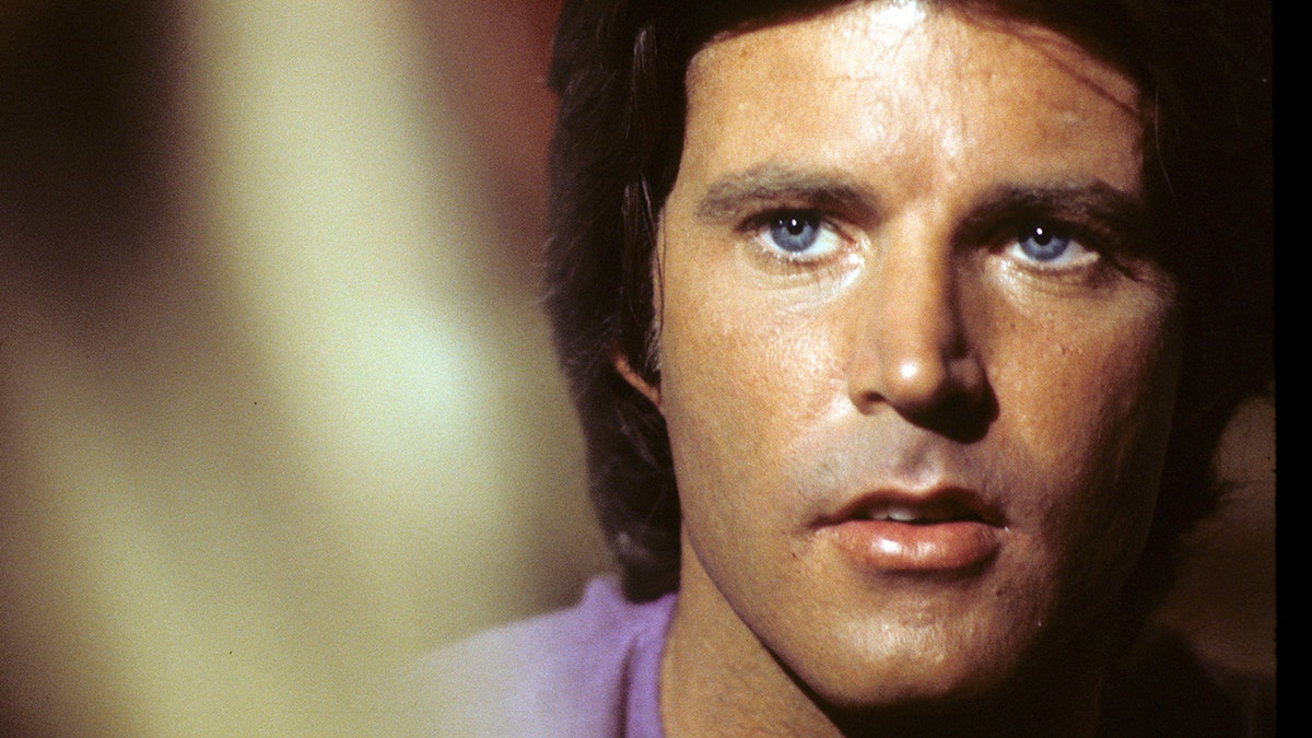 A close-up of Ricky Nelson next to gold light.