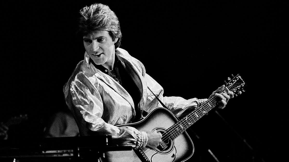 A black and white photo of Ricky Nelson playing guitar.