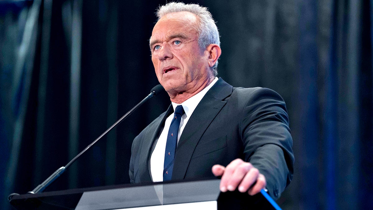 Robert F. Kennedy Jr. in a dark suit speaking from a podium