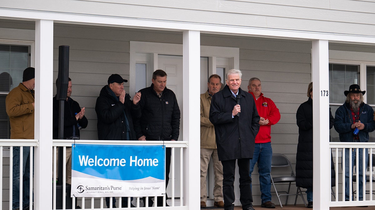 Rev. Graham speaking into microphone on porch at Chestnut Ridge