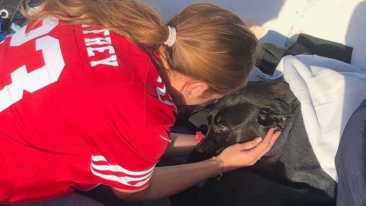 This photo released by San Diego Fire-Rescue shows owner Alexis reuniting with Sadie, a black Labrador retriever-mix, after Sadie was rescued from the water near Mission Beach, San Diego, Nov. 23, 2025. (San Diego Fire-Rescue via AP)