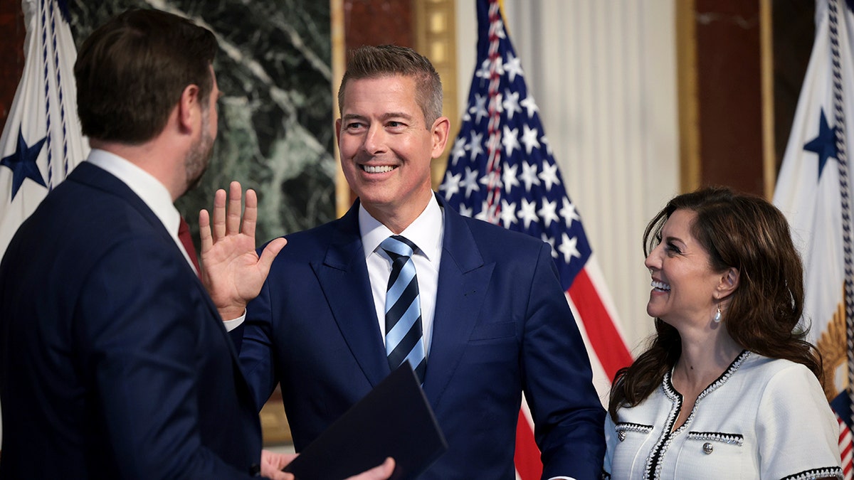 Vice President JD Vance, Sean Duffy who is smiling and holding his hand up, and Rachel Campos-Duffy, who smiles while holding the Bible at the swearing in for Sean Duffy to serve as Transportation Secretary
