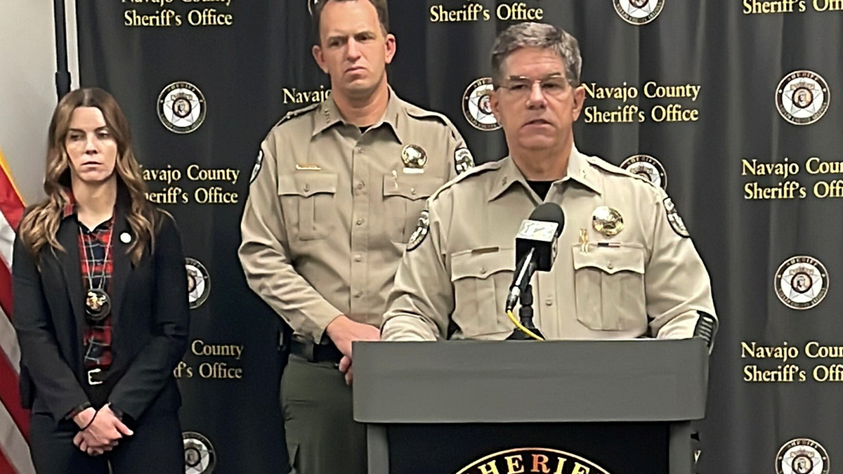 Navajo County Sheriff’s Office officials stand at a podium during a law enforcement news briefing in Arizona