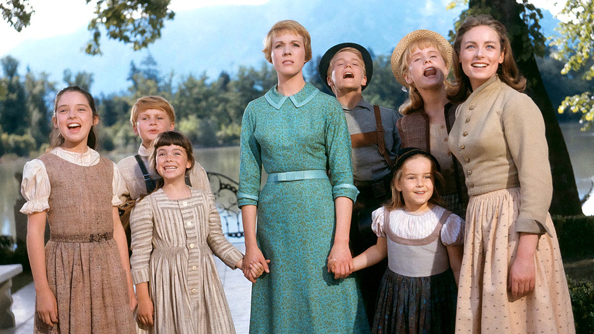 Julie Andrews stands with the child actors from 'The Sound of Music' in a posed group photo.