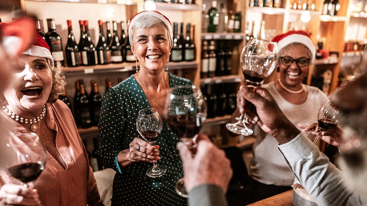 Older adults enjoying wine in bar with santa hats
