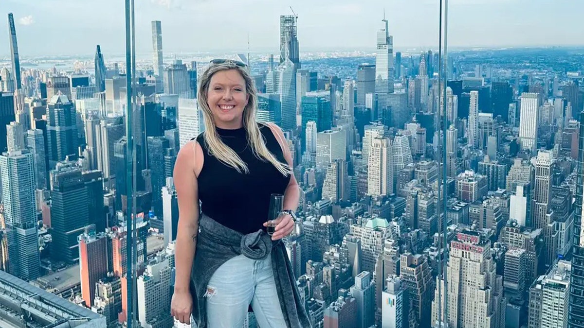 Blonde woman in black top in observation room of a sky tower.