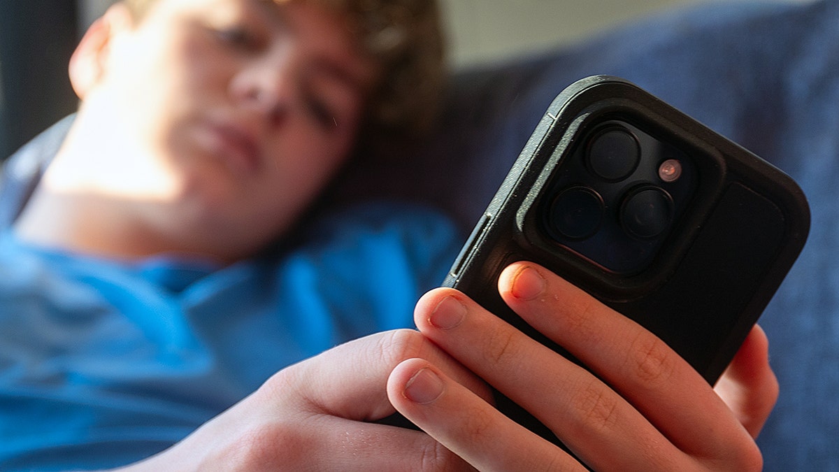 A 14-year-old boy looking at an iPhone screen in Bath, England