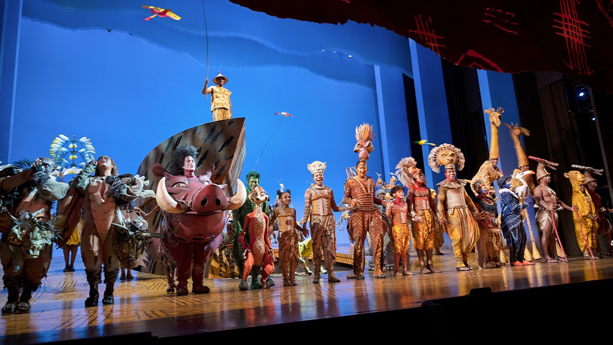 Actores de la producción de Broadway de «El rey león» en un escenario.
