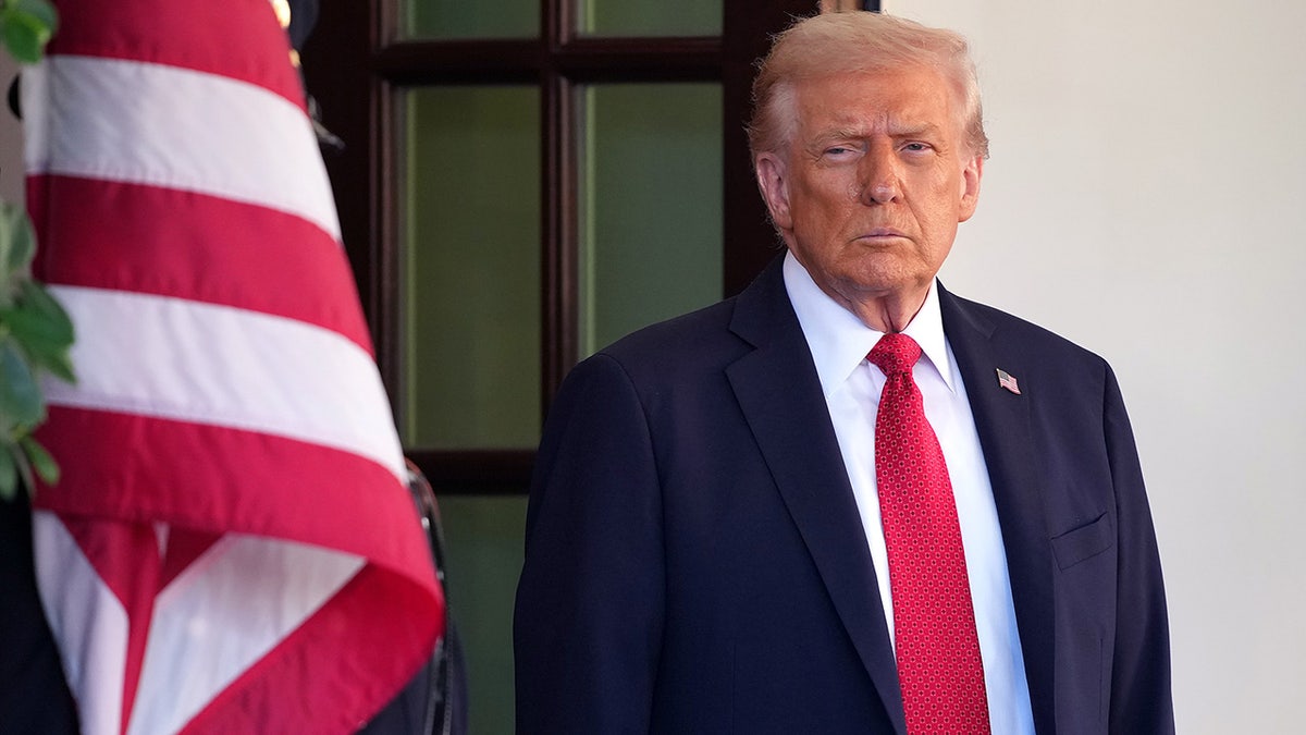 President Donald Trump stands next to an American flag