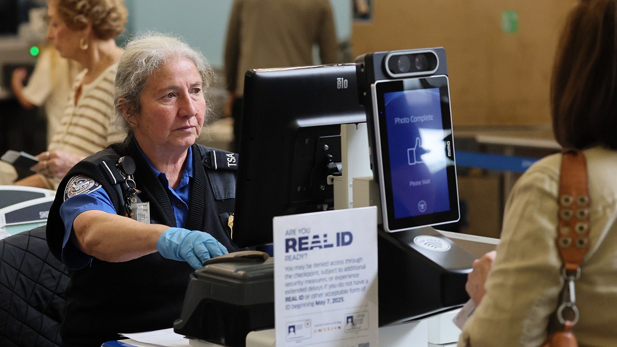 TSA officer checks a traveler’s ID using an automated security screening kiosk at an airport checkpoint.