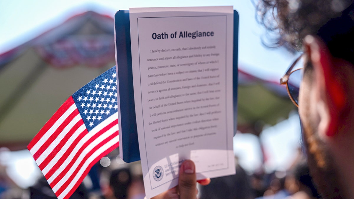 New U.S. citizen holds American flag and Oath of Allegiance