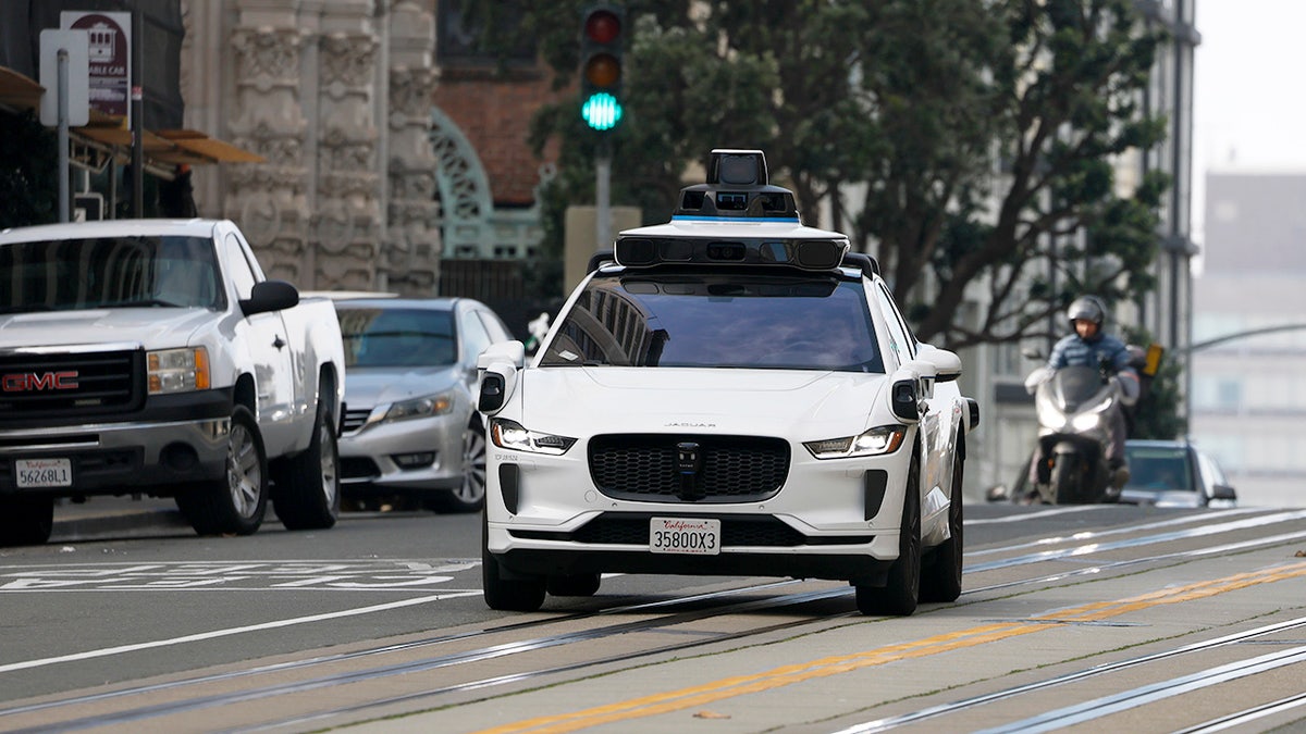Waymo self-driving taxi heads down street in San Francisco, California