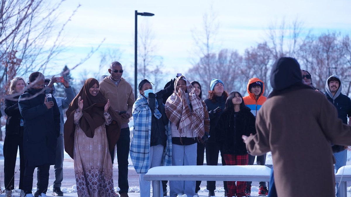 Group in snow jackets stands in circle