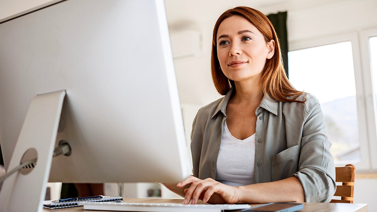 Woman types on desktop computer