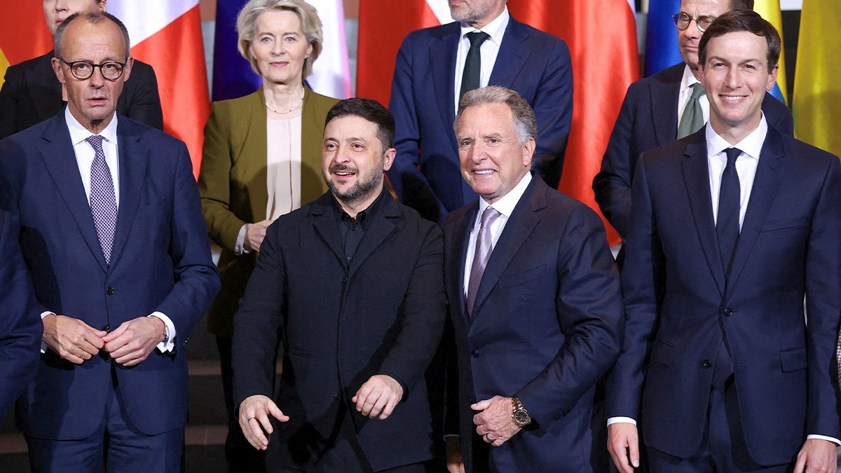 World leaders stand together in rows for a formal group photograph inside a government building.