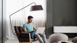 man sitting under floor lamp