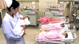 A nurse holds a newborn in a hospital