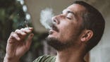A man smokes marijuana surrounded by smoke.
